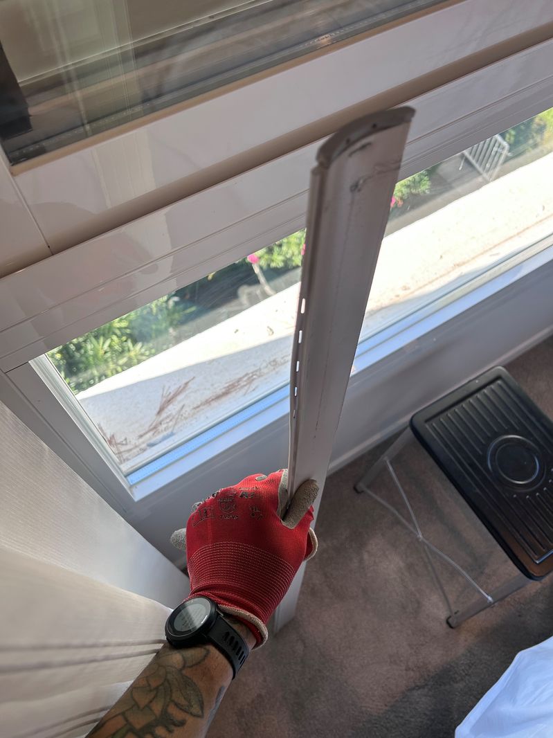 Técnico con guantes de trabajo retirando una pieza de una ventana de aluminio